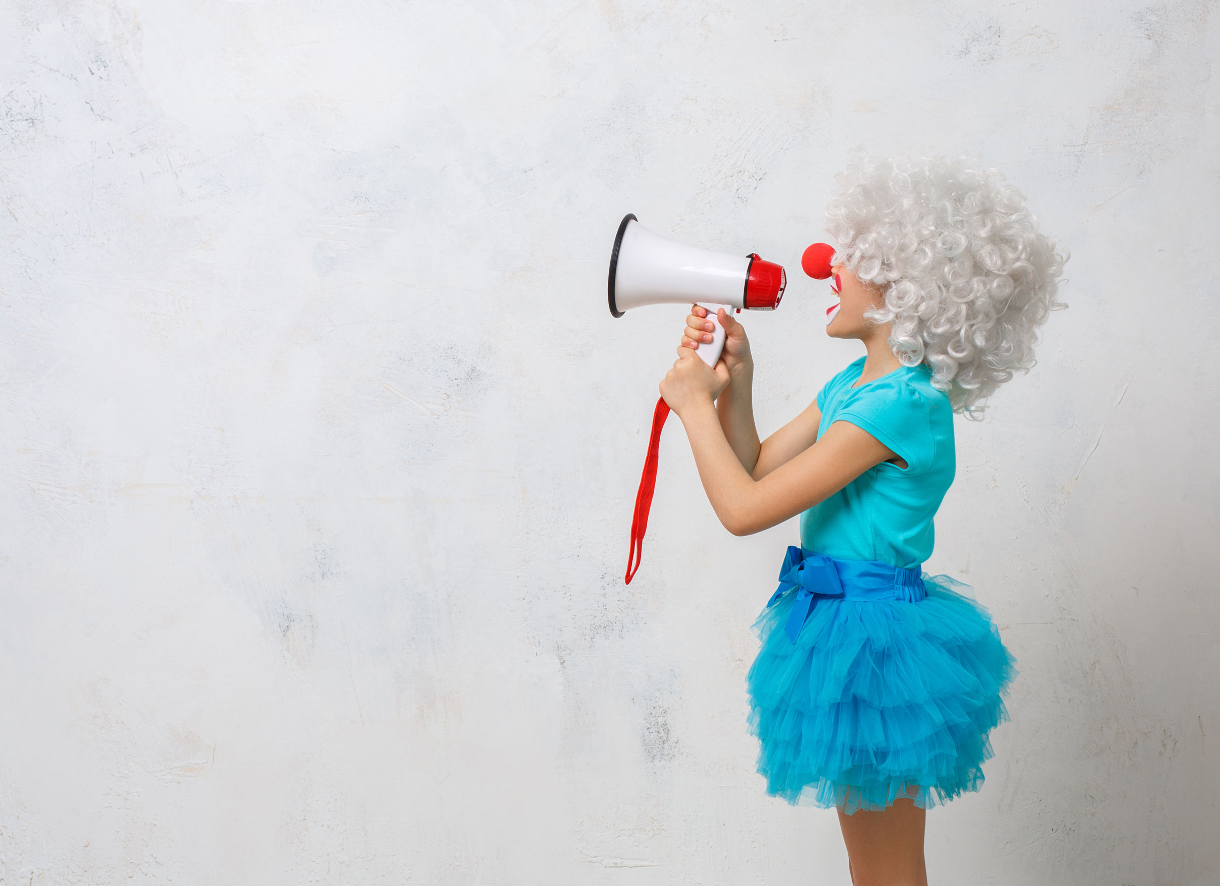 Side view of child in grey wig and cyan outfit speaking into a megaphone